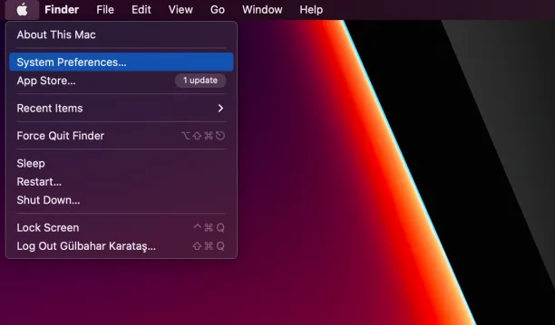 Mac desktop screenshot showing the Apple menu with 'System Preferences' highlighted in macOS menu bar.